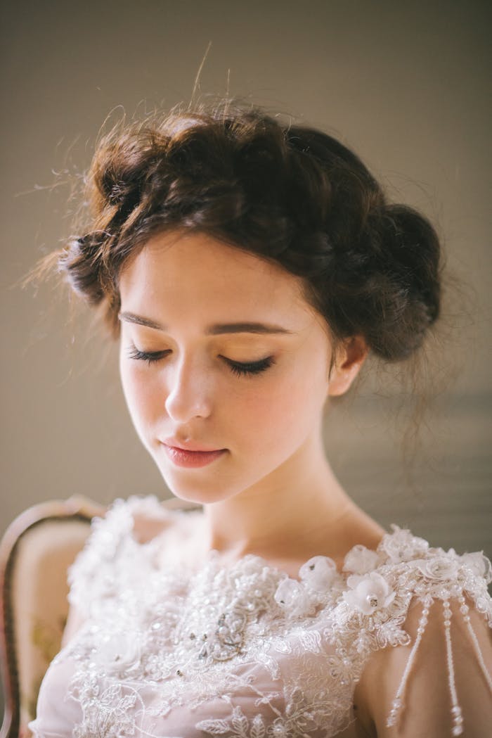 our-story Elegant brunette bride with floral hairdo, captured in soft lighting, highlighting her beauty and grace.